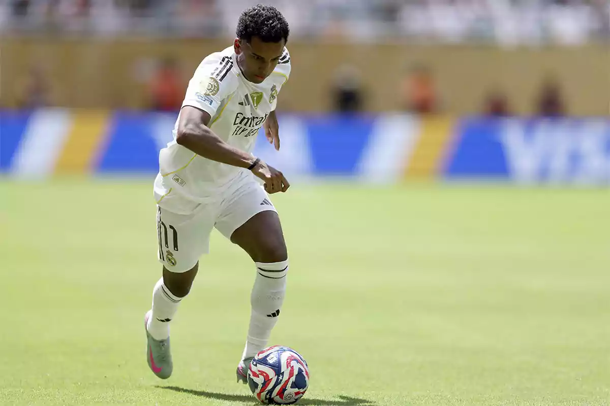 Soccer player in a white uniform controlling the ball on a soccer field during a match