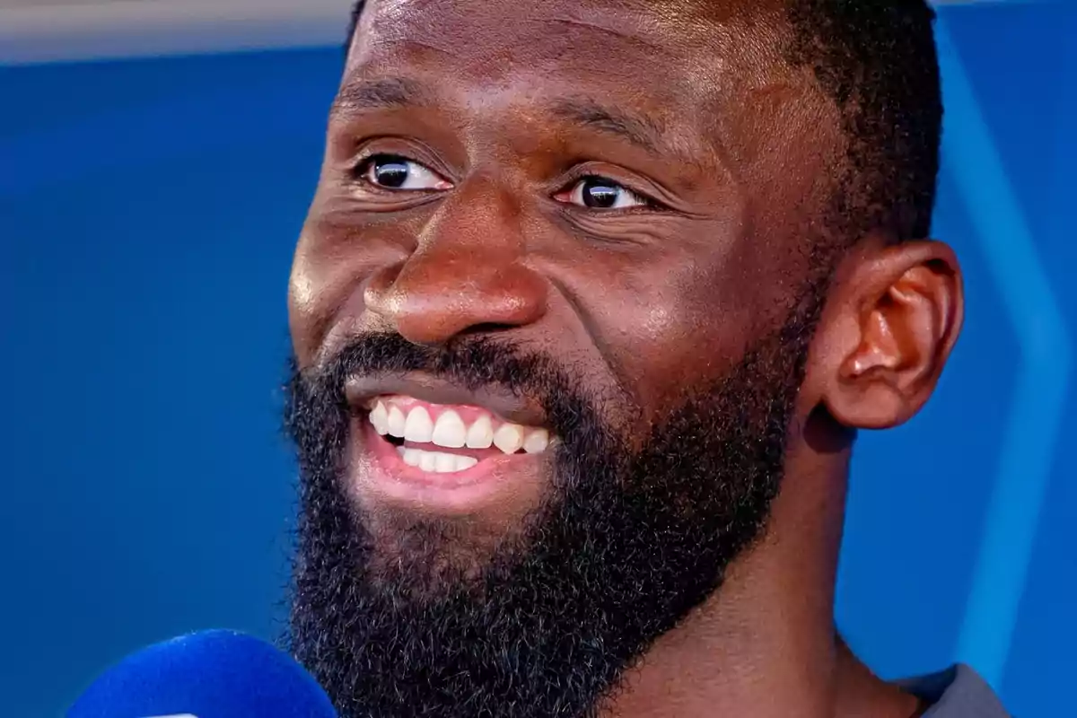 Antonio Rüdiger en primer plano mientras habla ante un micrófono de color azul