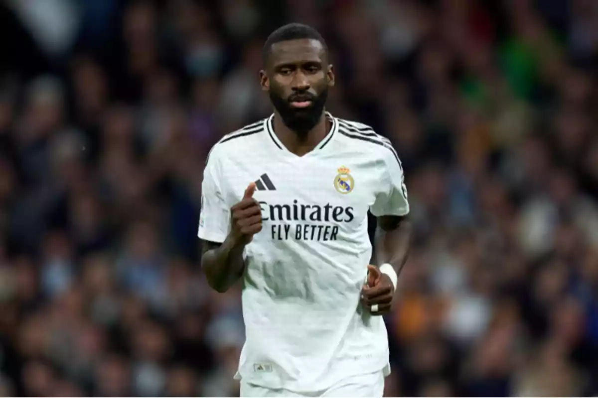 Un jugador de fútbol con el uniforme blanco del Real Madrid corriendo en el campo durante un partido.