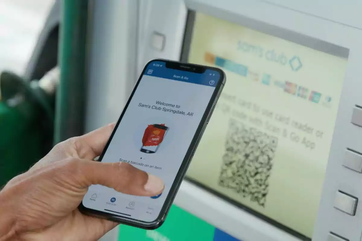 Una persona sostiene un teléfono móvil frente a una pantalla que muestra un código QR en Walmart. Una persona sostiene un teléfono móvil frente a una pantalla que muestra un código QR en Walmart.