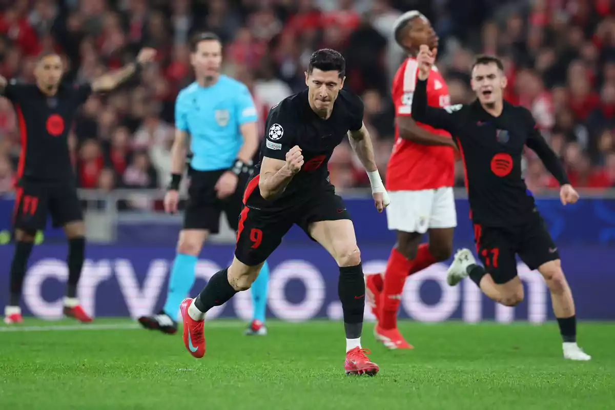A soccer player celebrates with a clenched fist in a match while other players and the referee are in the background. A soccer player celebrates with a clenched fist in a match while other players and the referee are in the background.