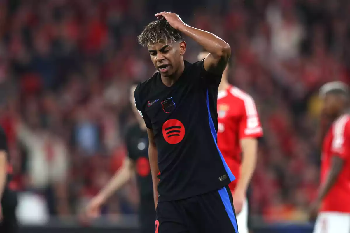 A soccer player in a black uniform touches his head on the field during a match. A soccer player in a black uniform touches his head on the field during a match.