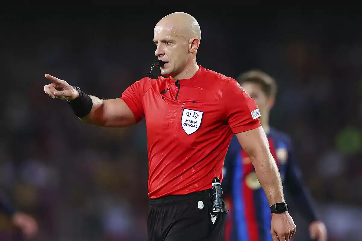 A soccer referee in a red uniform points with his finger during a match. A soccer referee in a red uniform points with his finger during a match.