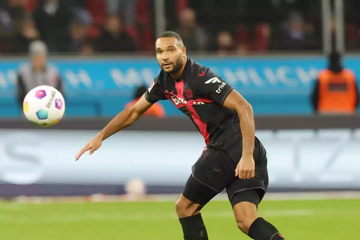 Football player in action during a match, wearing a black uniform with red details.