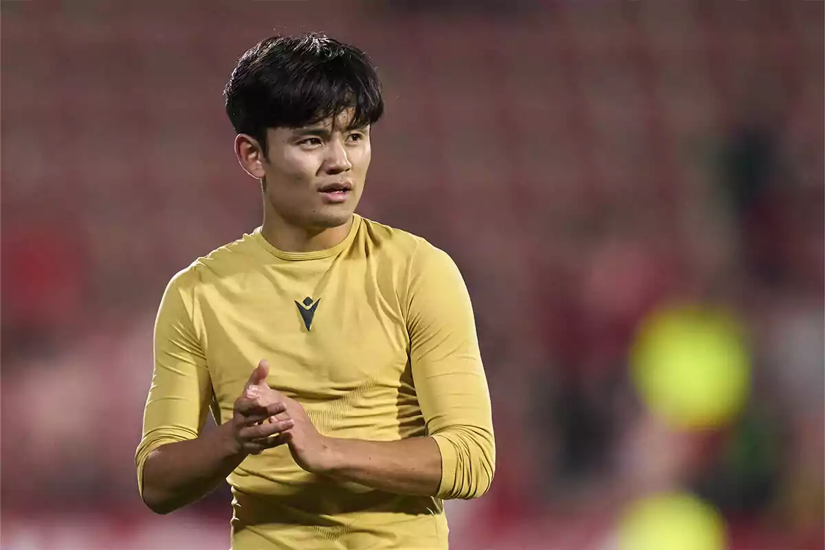 A player in a yellow jersey applauds in a stadium. A player in a yellow jersey applauds in a stadium.