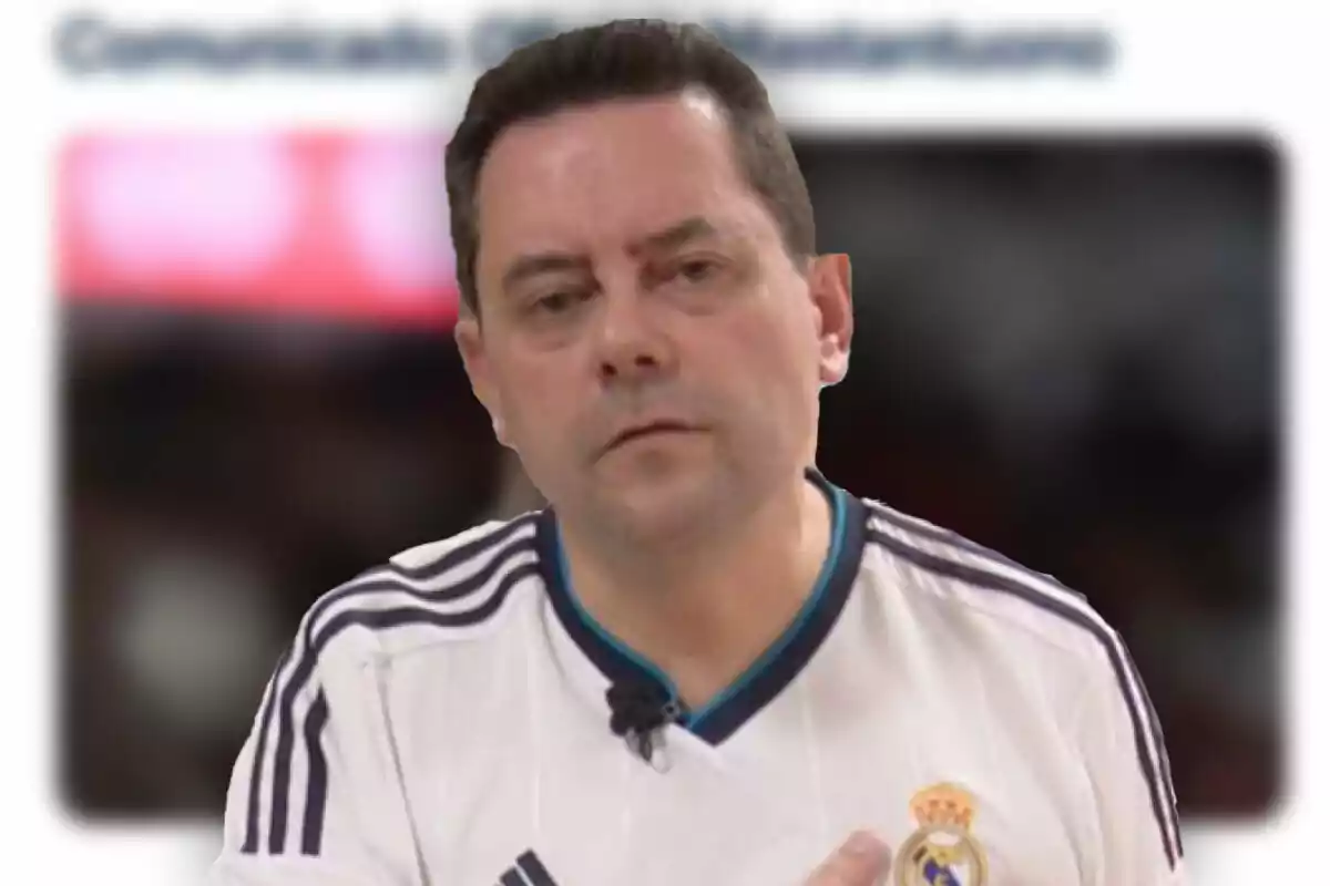 Hombre con expresión seria vistiendo una camiseta blanca del Real Madrid con fondo desenfocado