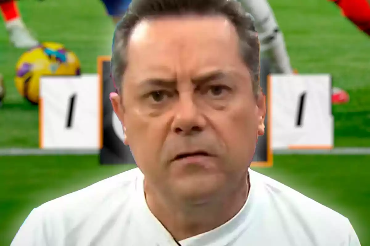 A man with a serious expression in the foreground with a soccer field and a 1-1 scoreboard in the background.