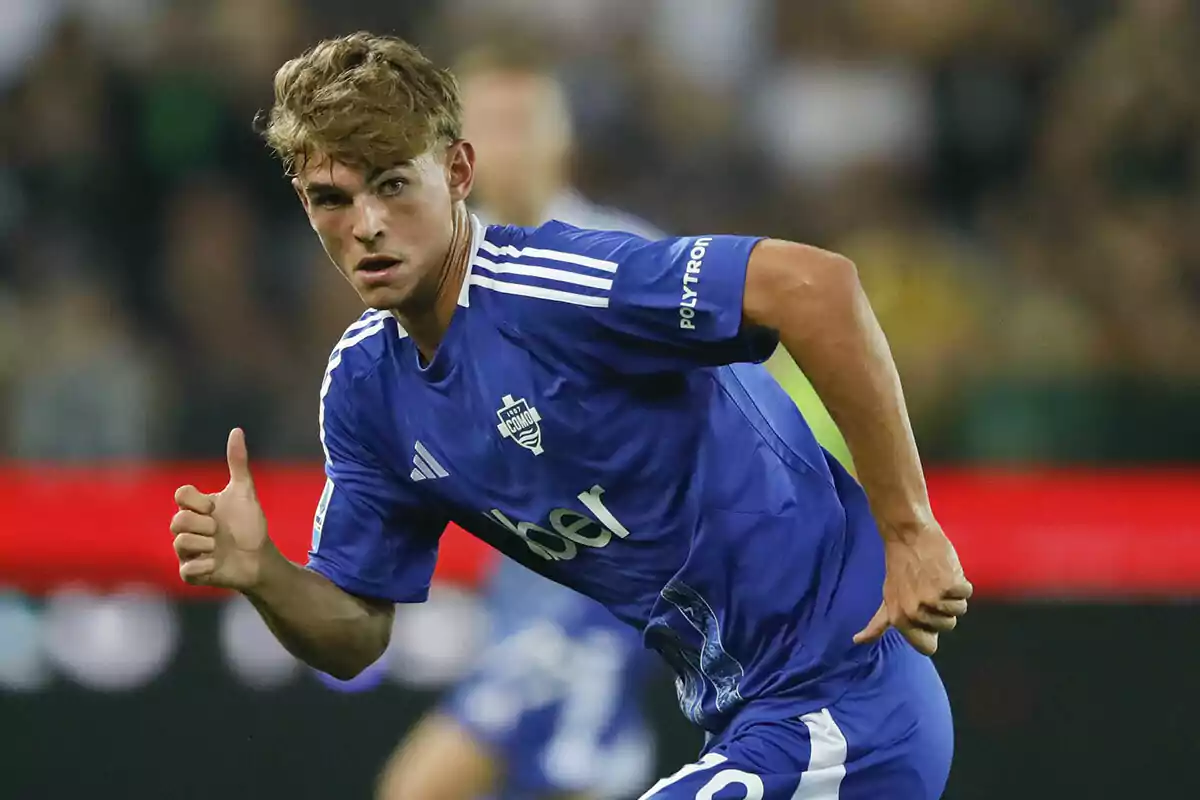 Nico Paz con uniforme azul del Como corre en el campo durante un partido.