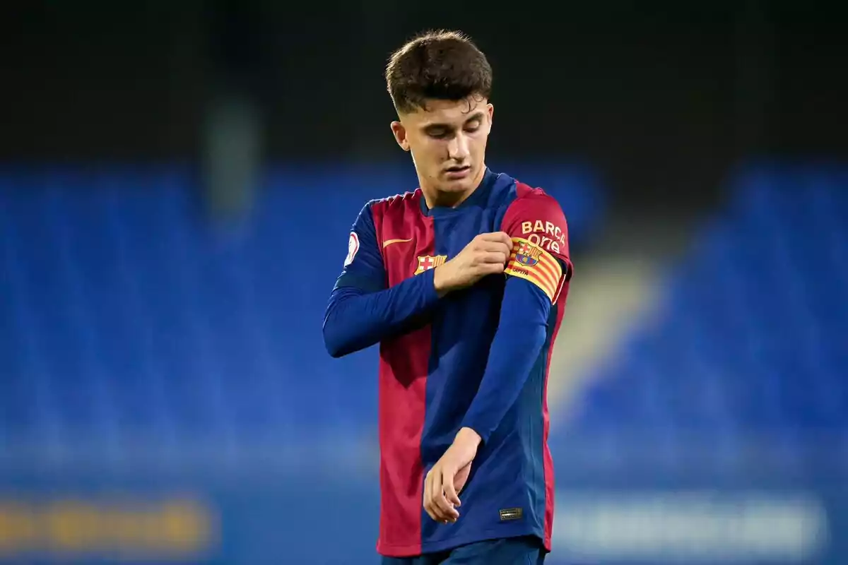 Un jugador de fútbol con el uniforme del FC Barcelona ajusta su brazalete de capitán en el campo.