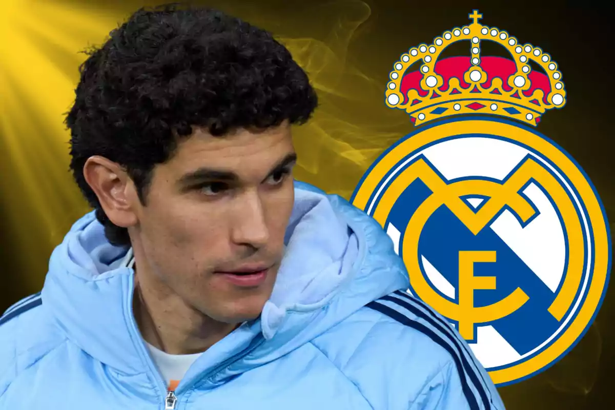 A man in a light blue jacket in front of the Real Madrid crest against a dark background with yellow lights.