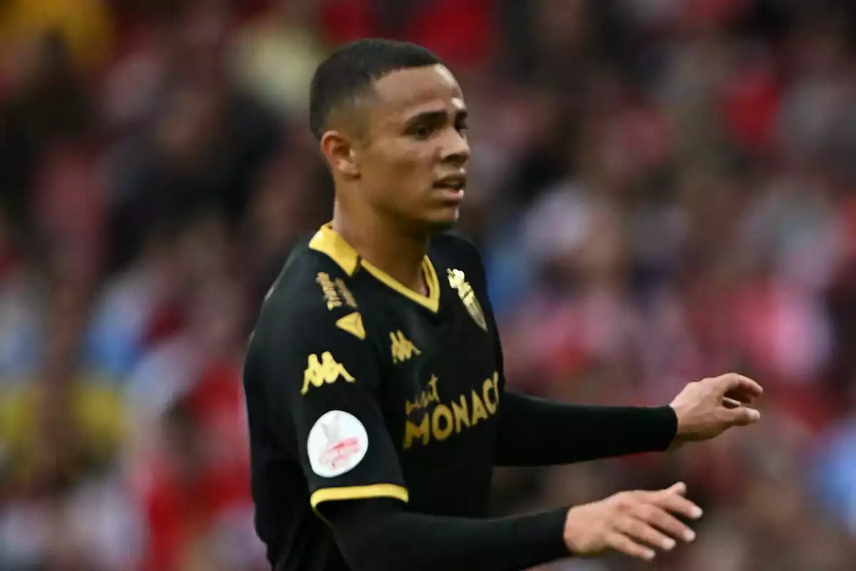 Jugador de fútbol con uniforme negro y dorado del Mónaco en el campo de juego.