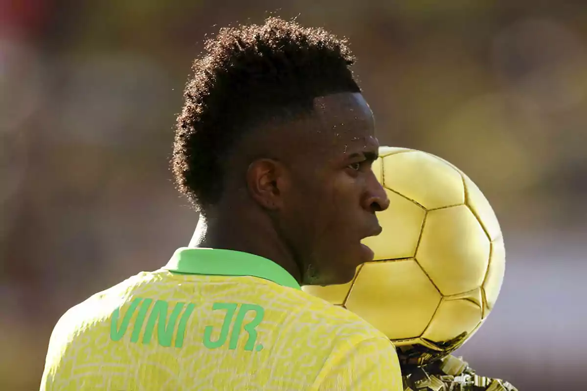 Vinicius Jr con la camiseta de Brasil, detrás el Balón de Oro.