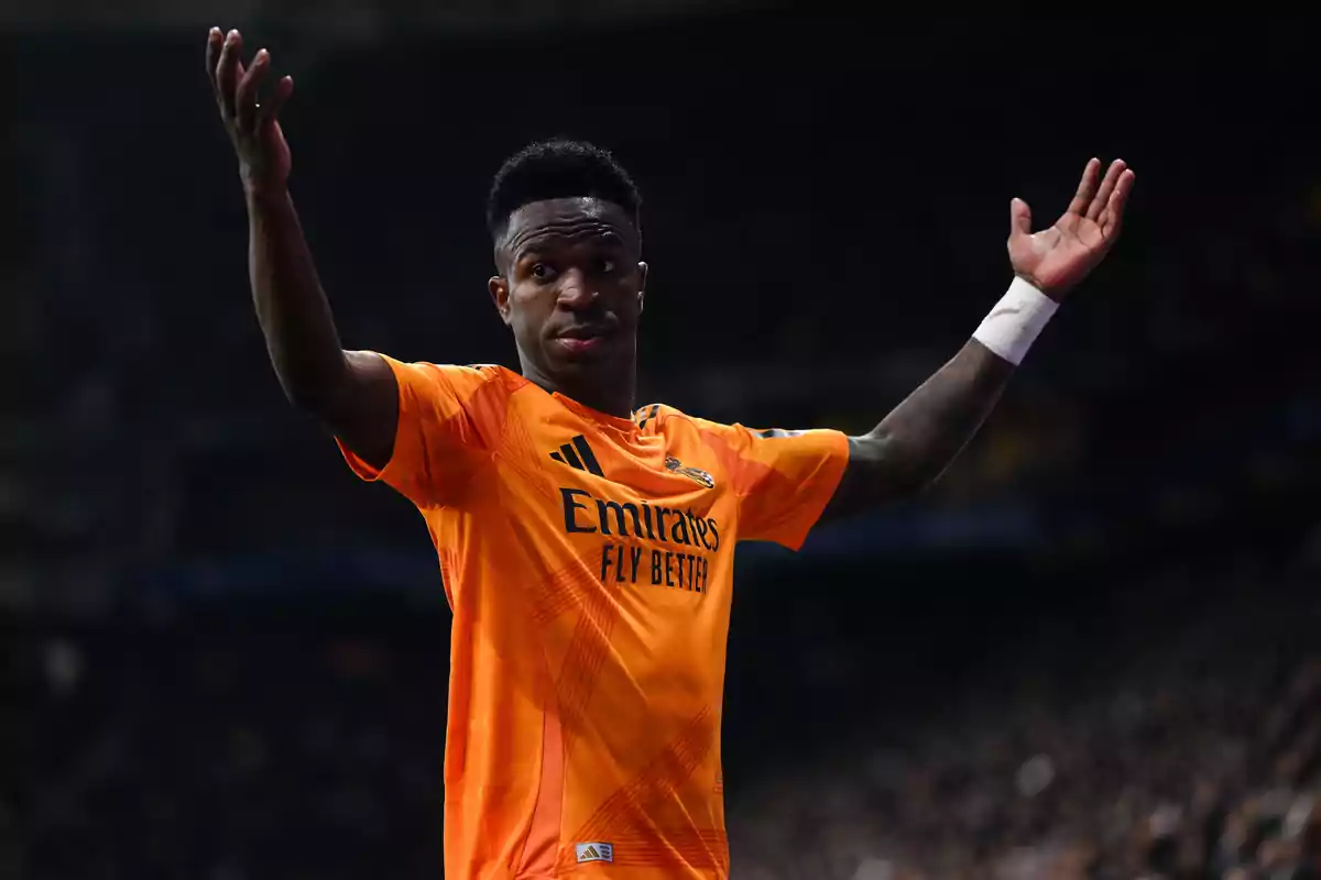 A player in an orange uniform raises his arms in a gesture of questioning or surprise during a match.