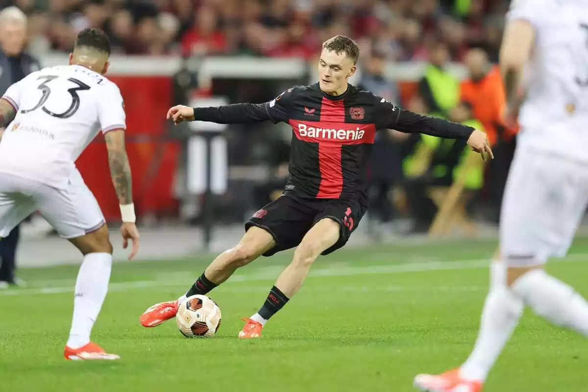 Florian Wirtz tries to make a pass between two rivals with the Bayer shirt