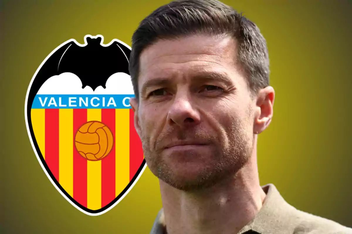 Un hombre de cabello corto y barba ligera está frente al escudo del Valencia CF sobre un fondo amarillo.