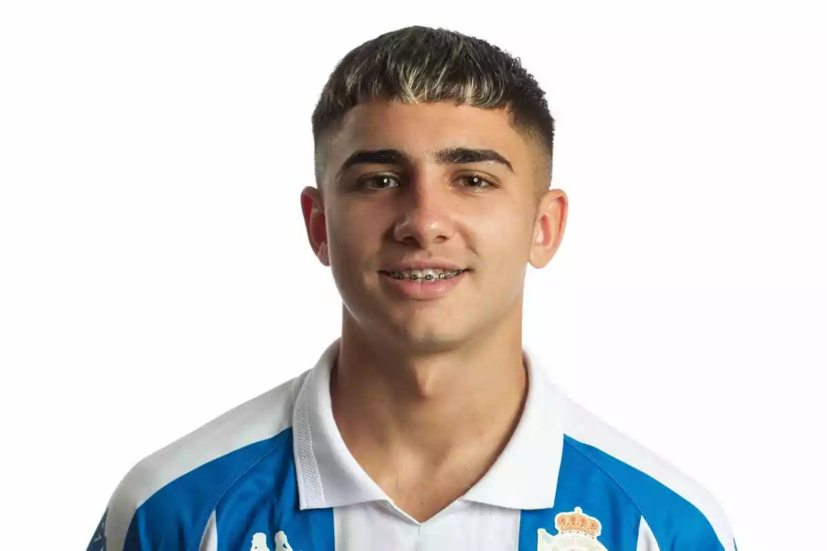 Un joven con camiseta deportiva azul y blanca sonriendo a la cámara. Un joven con camiseta deportiva azul y blanca sonriendo a la cámara.