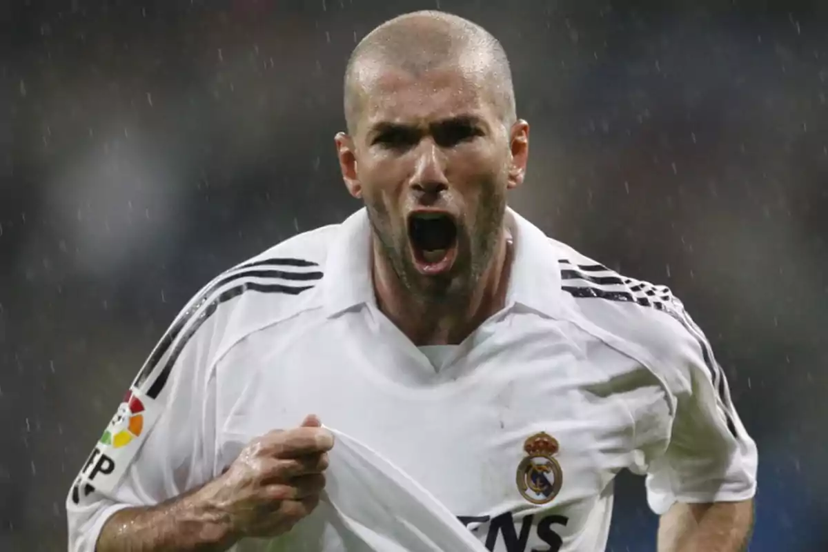 Zinedine Zidane celebrando con pasión bajo la lluvia mientras viste la camiseta del Real Madrid.